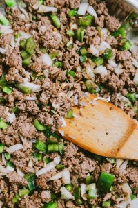 Ground beef in a pan with onions and green peppers.