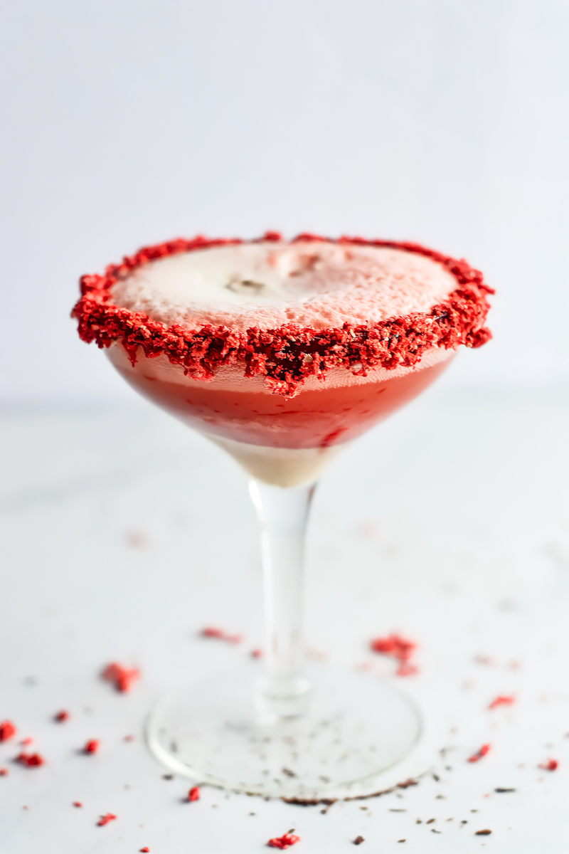 A martini with red and white sprinkles on top.