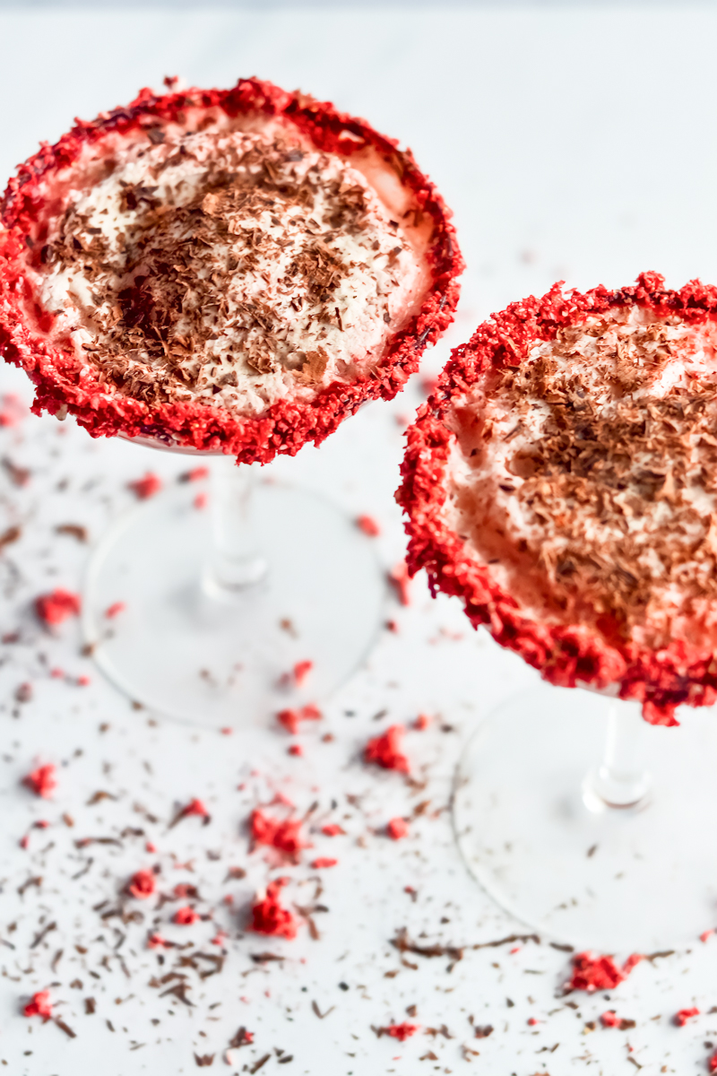 Two red velvet martinis on a white surface.