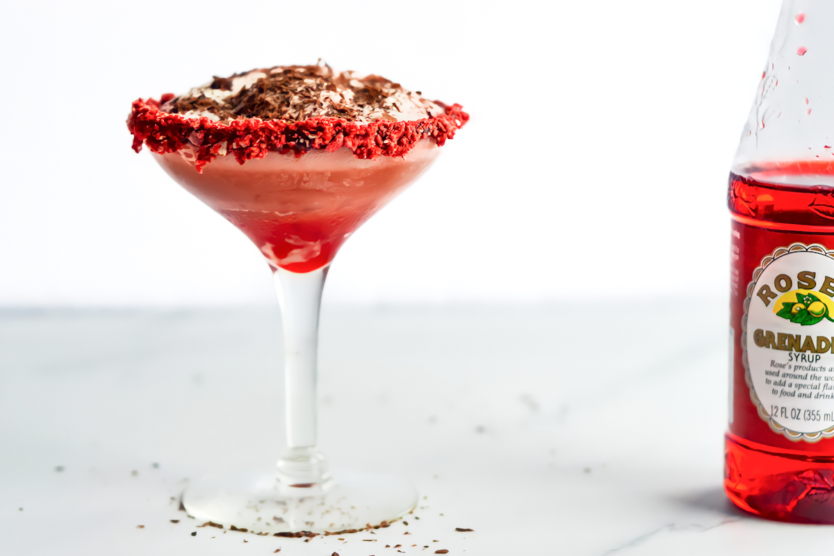 A martini glass with whipped cream and a bottle of red wine.