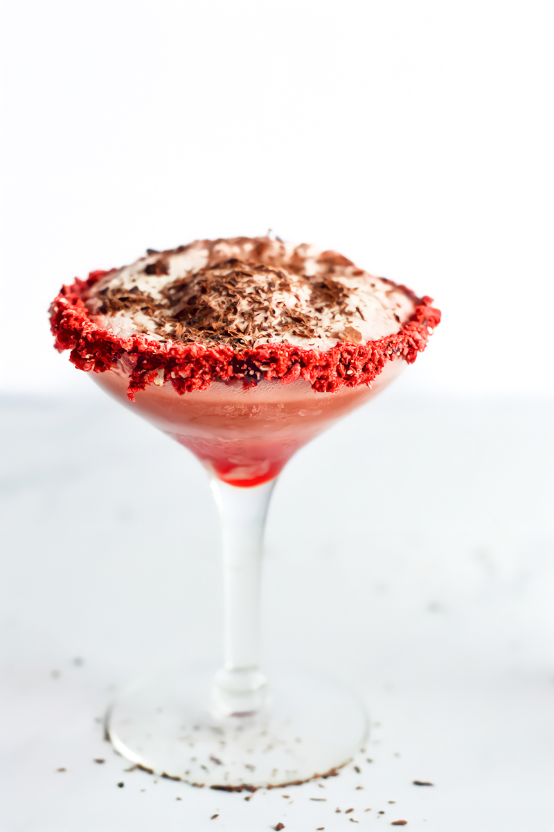 A martini with whipped cream and a cherry on top.