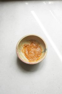 A bowl of orange sauce sitting on a counter.