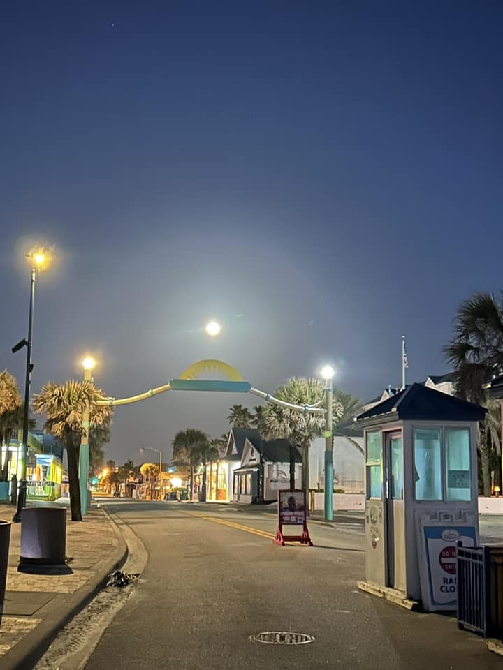 An image of a street at night with a full moon.