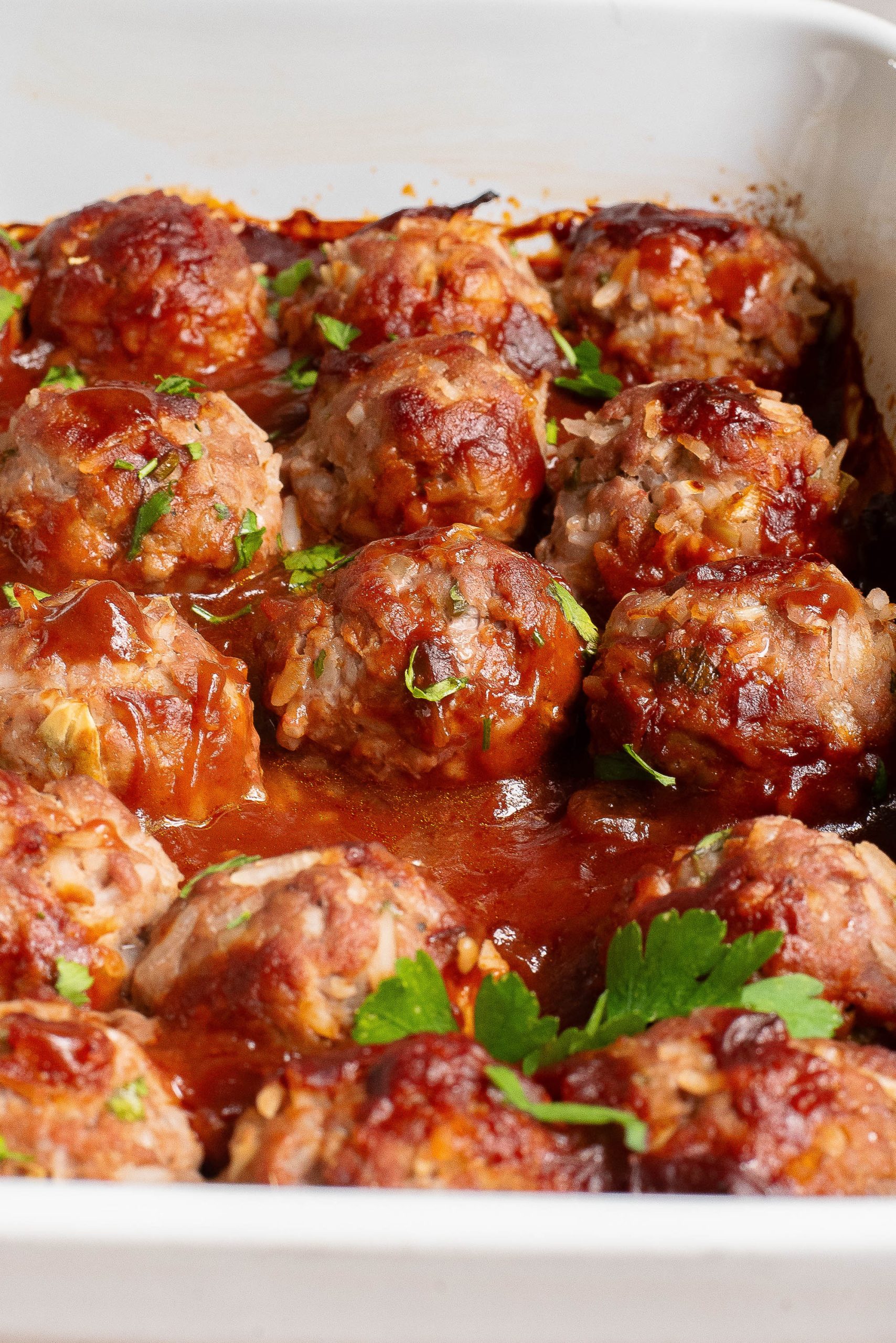 Meatballs in a pan with sauce and parsley.