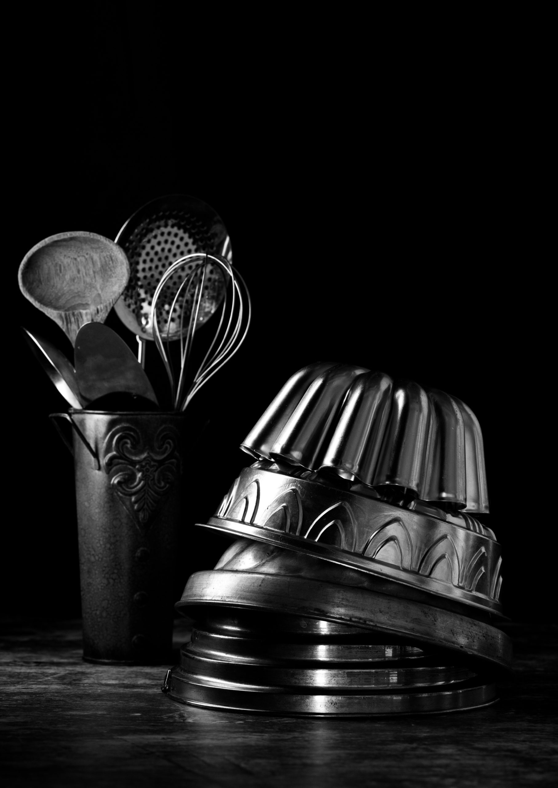 Assorted vintage baking pans and kitchen utensils in monochrome.