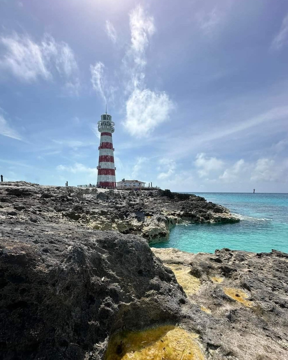 A lighthouse sits on top of a rock next to the ocean, offering things to do in New Smyrna Beach.