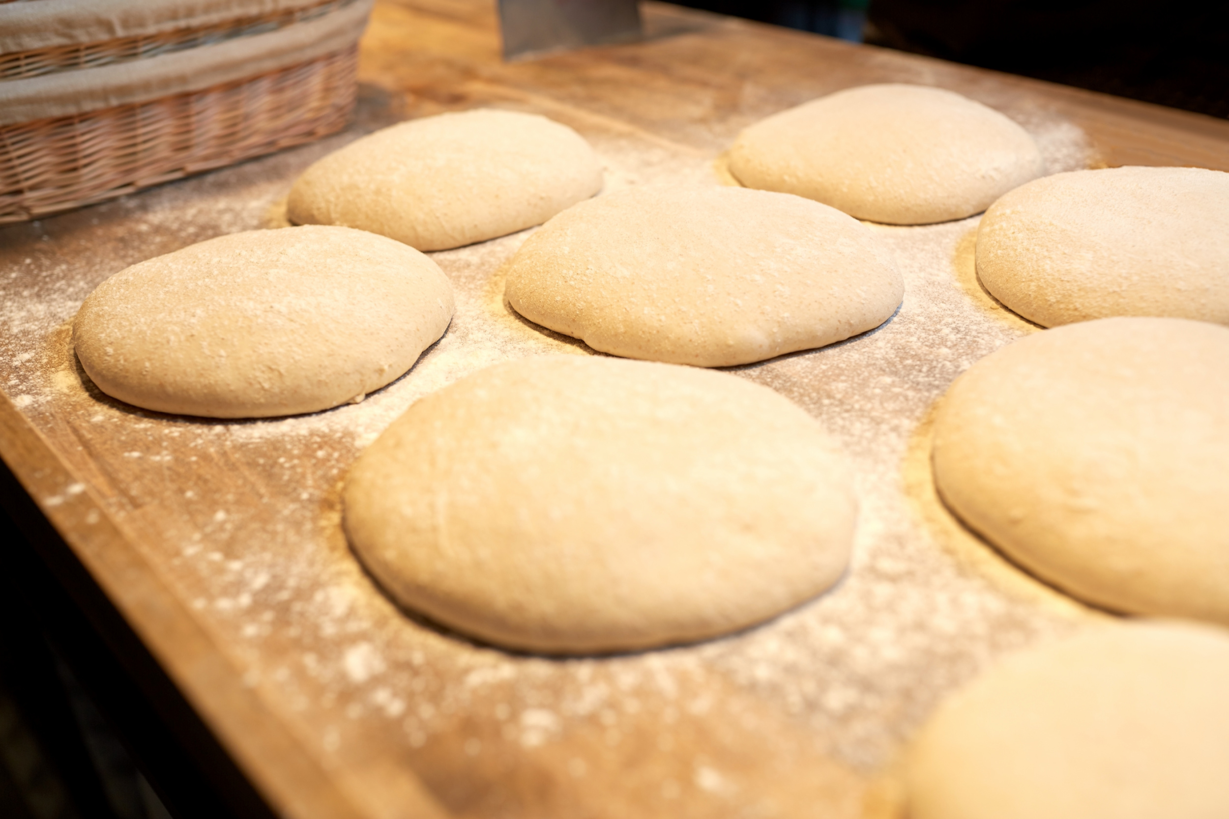Unbaked yeast bread dough shaped into rounds and resting on a floured surface, ready for freezing.