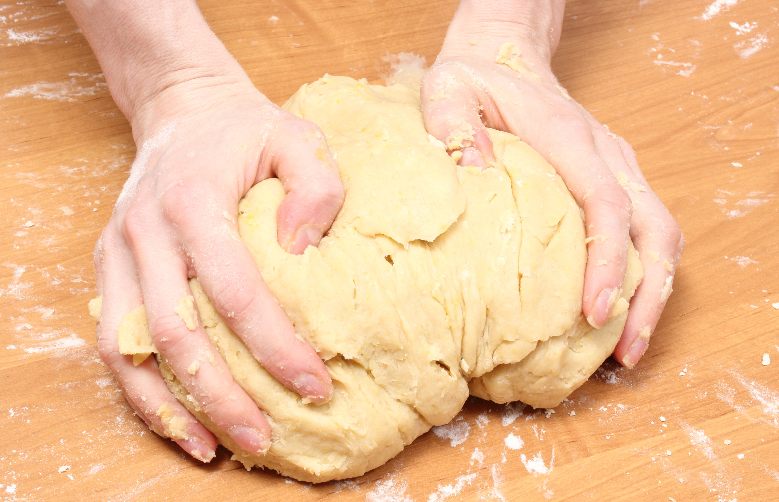 Kneading freezing yeast bread dough on a floured wooden surface.