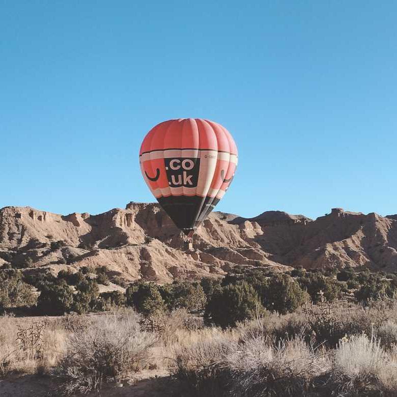 Hot air balloon floating over a desert landscape at sunrise, one of the must-do activities in Santa Fe.