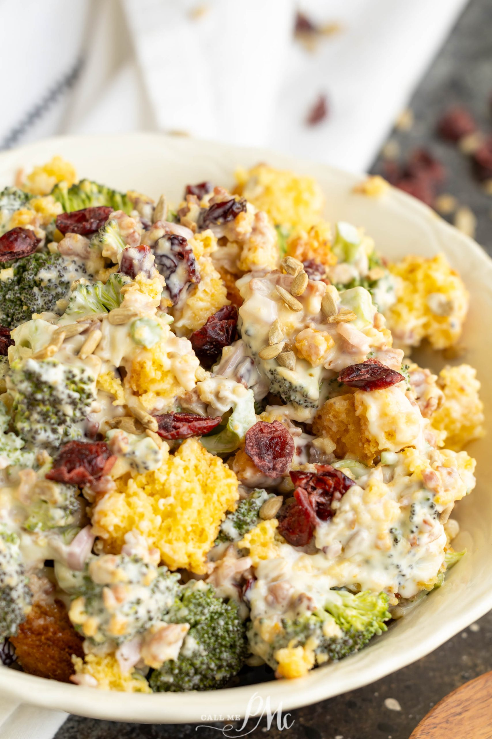 A bowl full of with dried cranberries and nuts, garnished with fresh herbs.