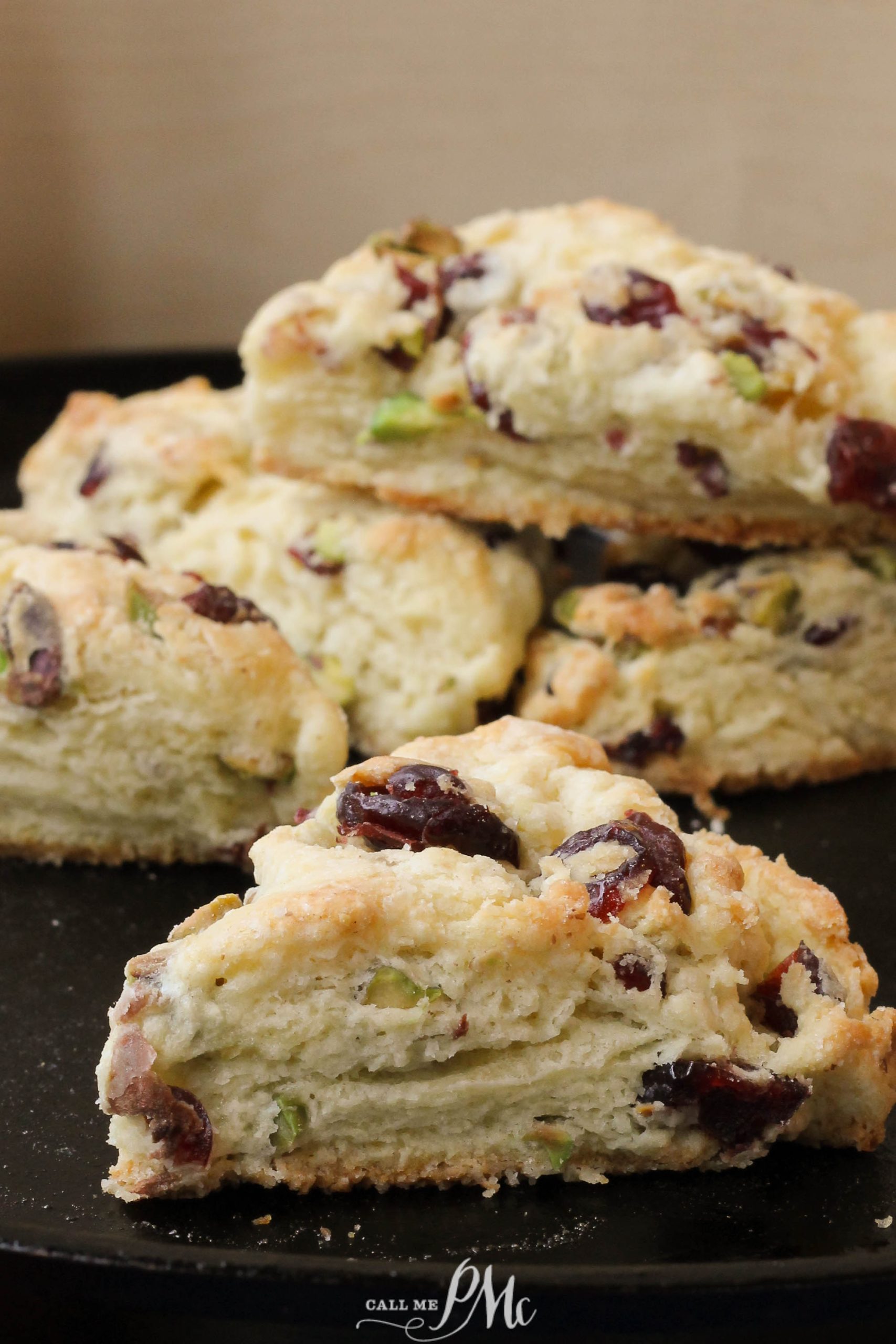 Freshly baked biscuits with fruit on a black plate.