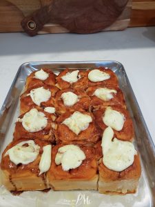 A tray of freshly baked cinnamon rolls topped with cream cheese frosting.