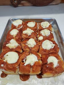 A tray of freshly baked cinnamon rolls topped with cream cheese frosting.