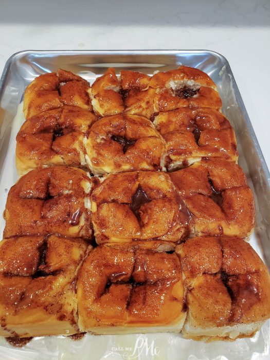 A tray of freshly baked cinnamon rolls with glaze.