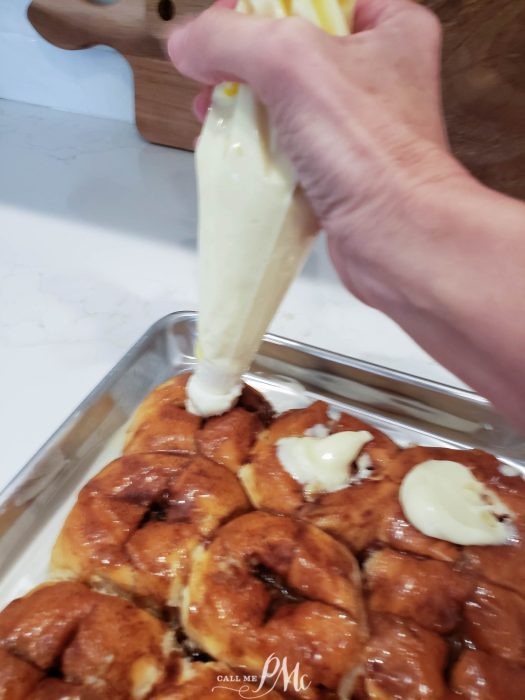 Applying icing to freshly baked cinnamon rolls.