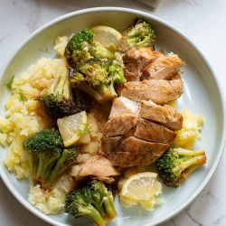 Grilled chicken breast slices with broccoli and mashed cauliflower on a plate.