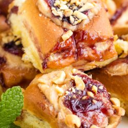 Glazed fruit pastries topped with crushed nuts, displayed with a garnish of fresh mint leaves.