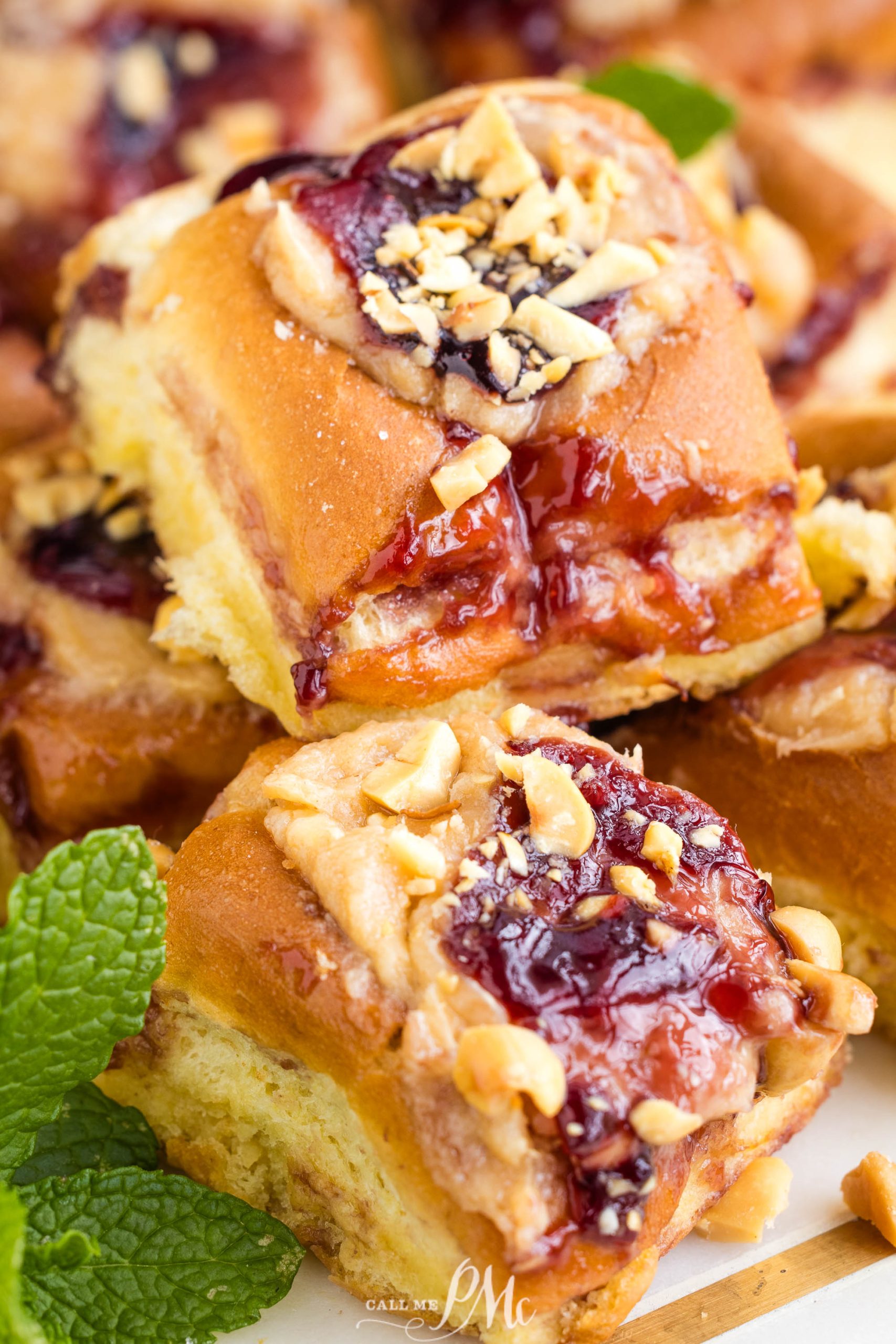 Peanut Butter and Jelly Hawaiian Roll Cheese Danish topped with crushed nuts, displayed with a garnish of fresh mint leaves.