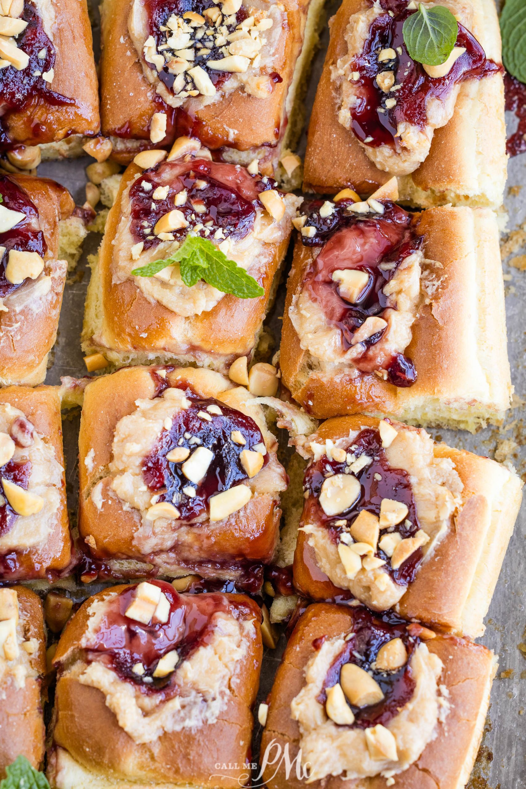 A tray of freshly baked Peanut Butter and Jelly Hawaiian Roll Cheese Danish topped with peanuts.