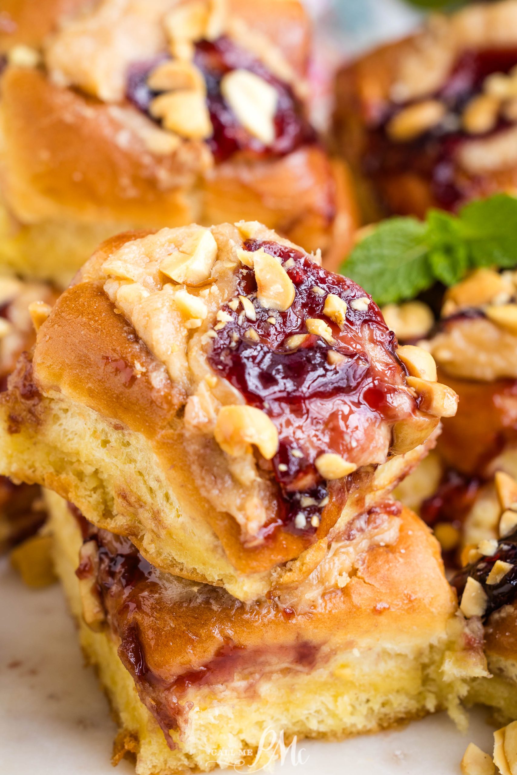 Close-up of a pb&j sticky bun topped with chopped nuts and a drizzle of glaze.