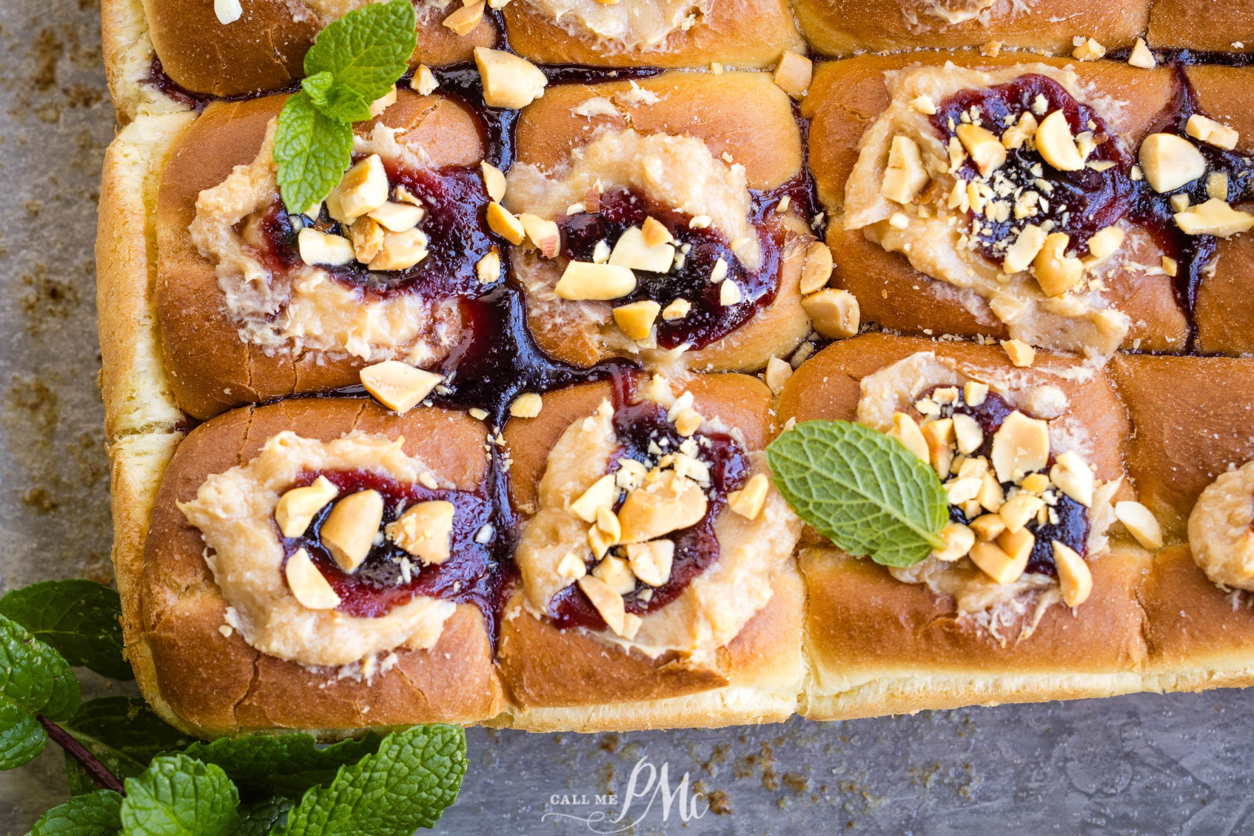 A close-up of a freshly baked Peanut Butter and Jelly Hawaiian Roll Cheese Danish with fruit jam, nuts, and peanut butter.