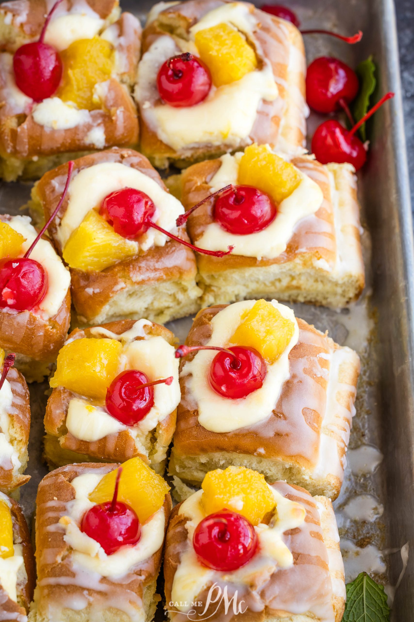 A tray of freshly glazed fruit-topped pastries with cherries and citrus.