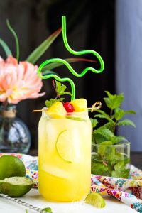A glass of yellow liquid with fruit on top.