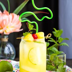 A glass of yellow liquid with fruit on top.