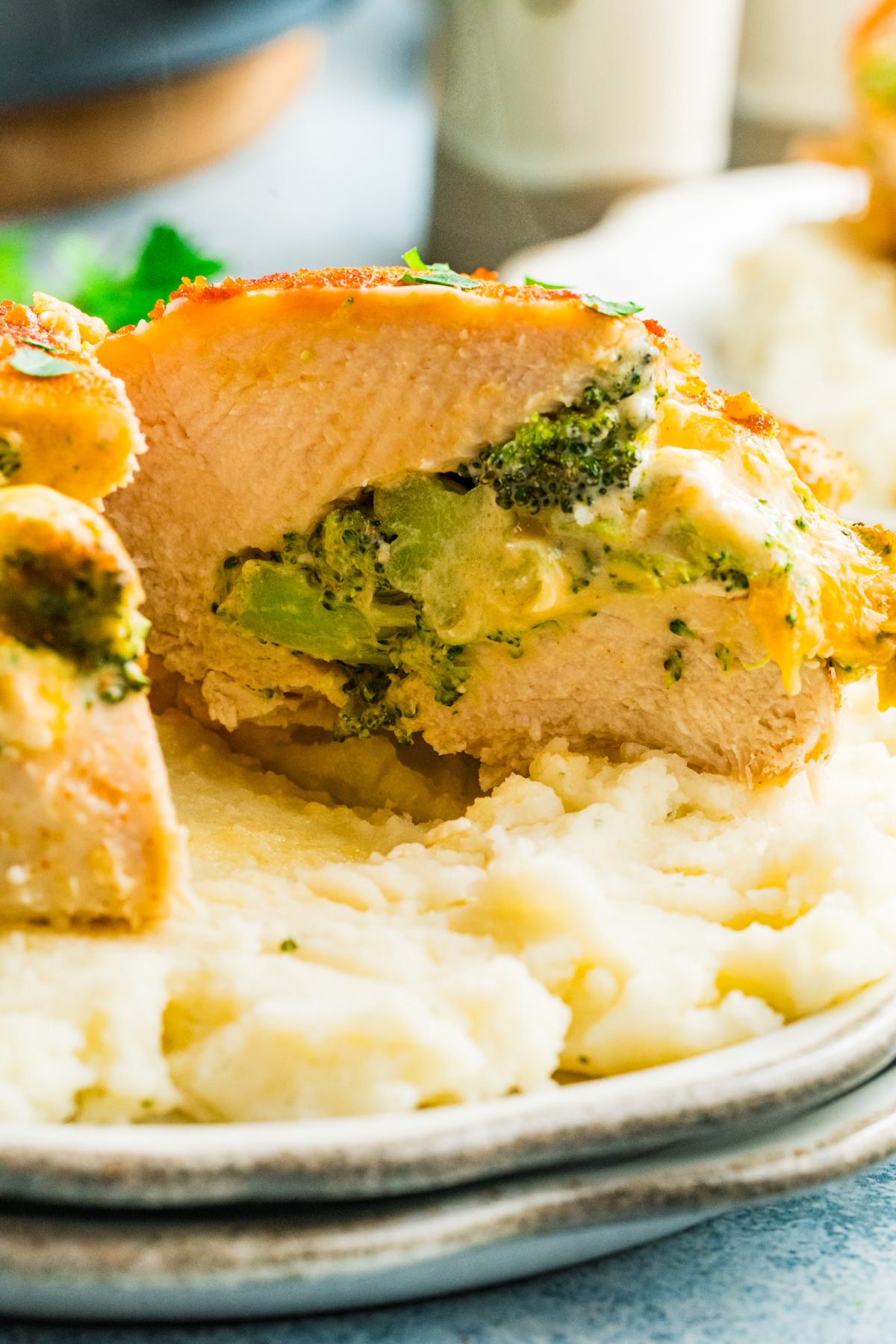 Broccoli stuffed poultry on a white plate with mashed potatoes.