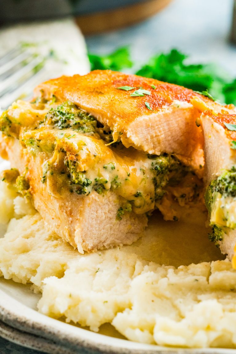 Broccoli stuffed buffalo chicken breasts, sliced and filled with cheese, are served on a bed of creamy mashed potatoes.