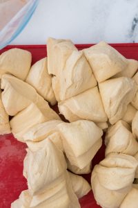 Close-up of raw, cut dough pieces on a red surface.