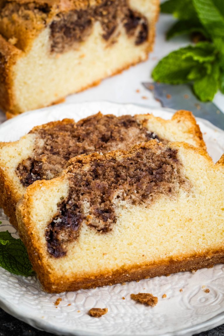 Two slices of Nutella Marble Pound Cake are served on a white plate, with a loaf and mint leaves in the background.