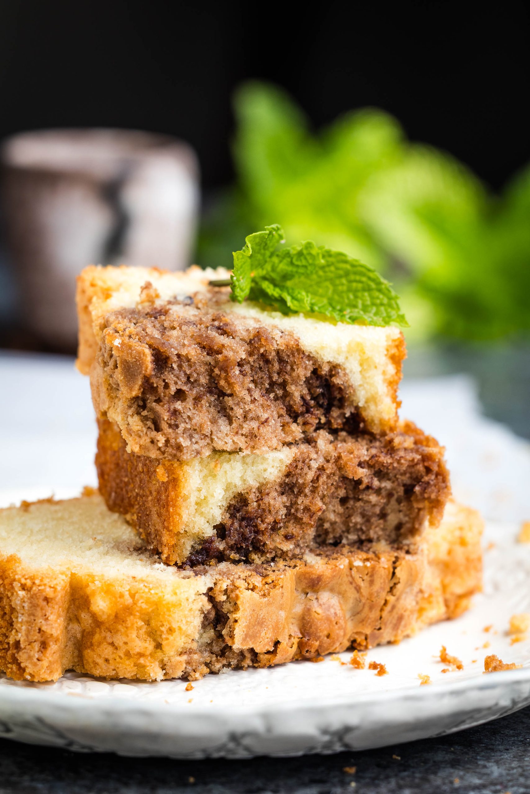 Three slices of Nutella Marble Pound Cake stacked on a white plate, garnished with a fresh mint leaf.