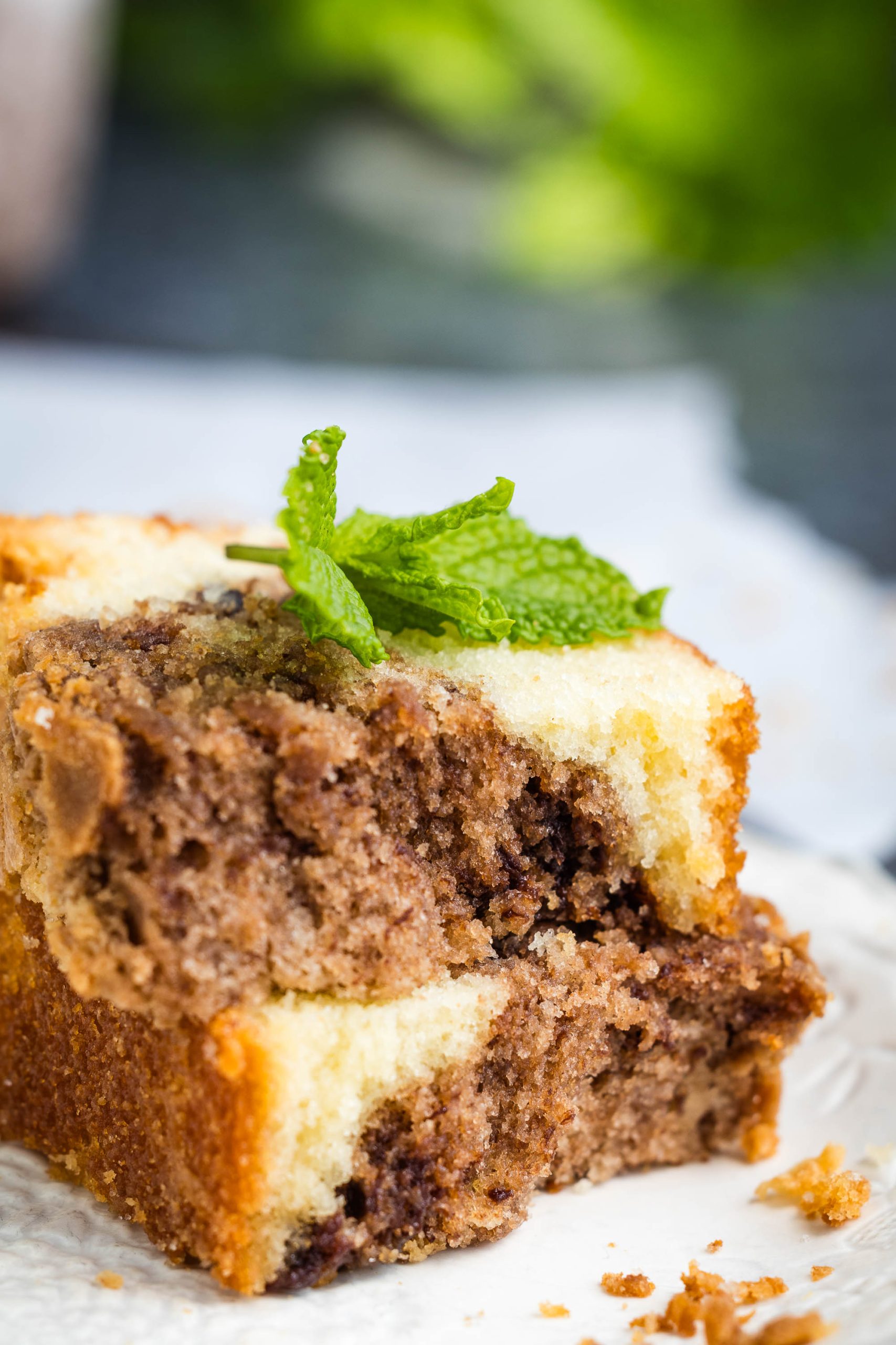 Two slices of Nutella Marble Pound Cake are stacked on a white surface, garnished with a sprig of mint on top.