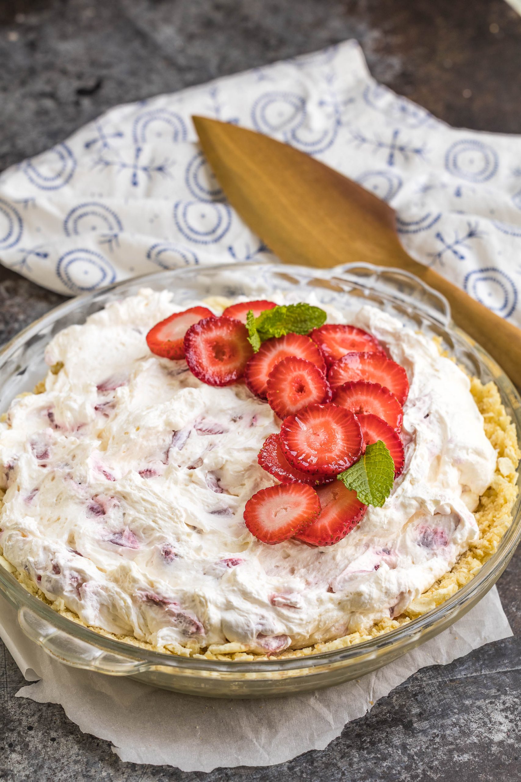 A dessert in a glass pie dish sits on a table. A pie server sits in the background.