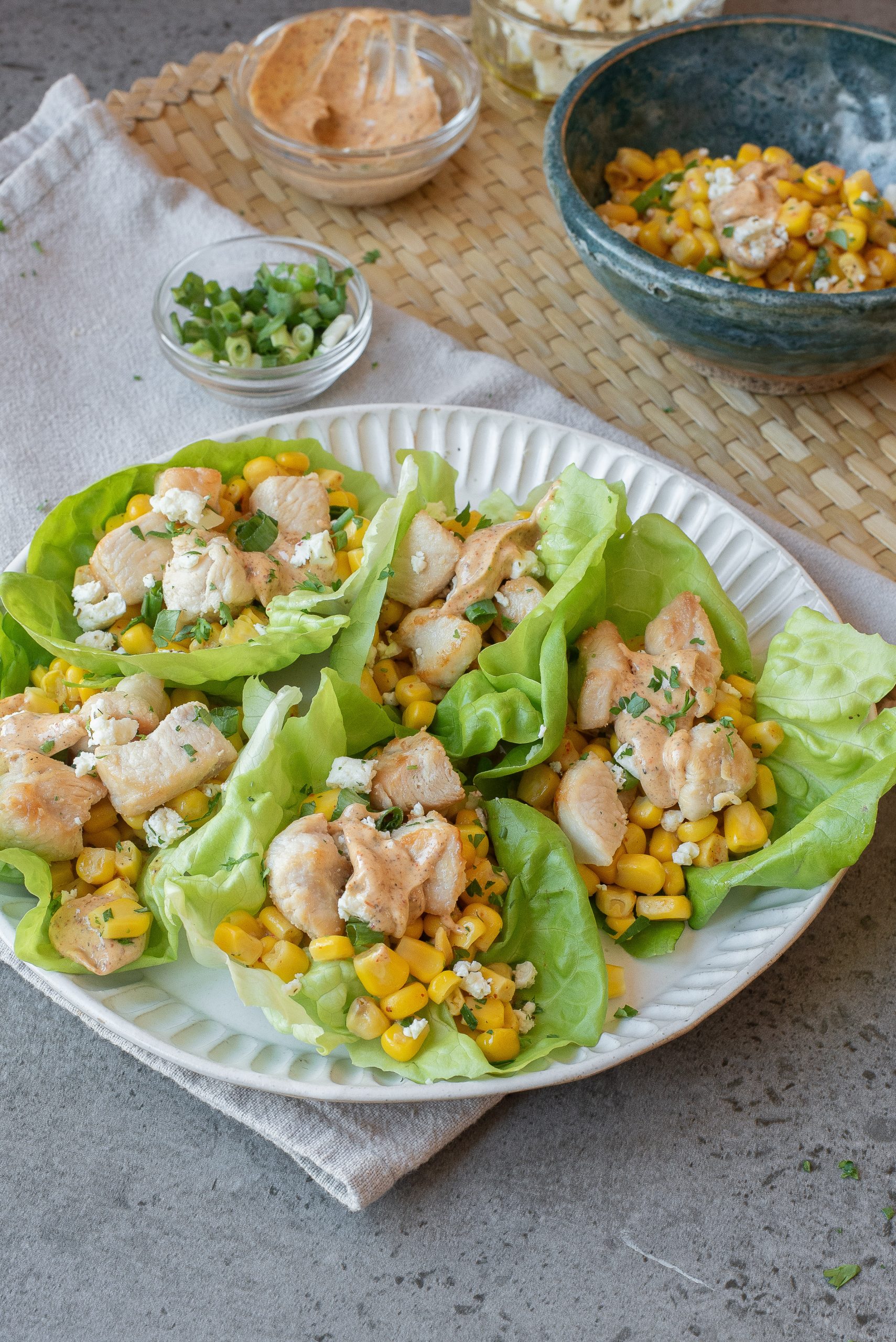 A plate with food and small bowls of sauce, green onions, and extra filling are nearby.