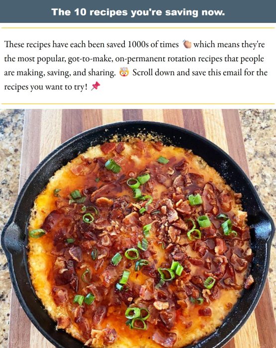 A cast iron skillet filled with a cheesy, baked dip topped with chopped bacon and sliced green onions sits on a wooden surface.