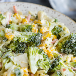 A plate of broccoli corn slaw mixed with shredded carrots and tossed in a creamy dressing.
