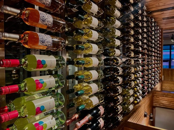 A wall-mounted wine rack at Harvey's Tupelo MS displays multiple rows of assorted wine bottles in a dimly lit room with wooden walls and ceiling.