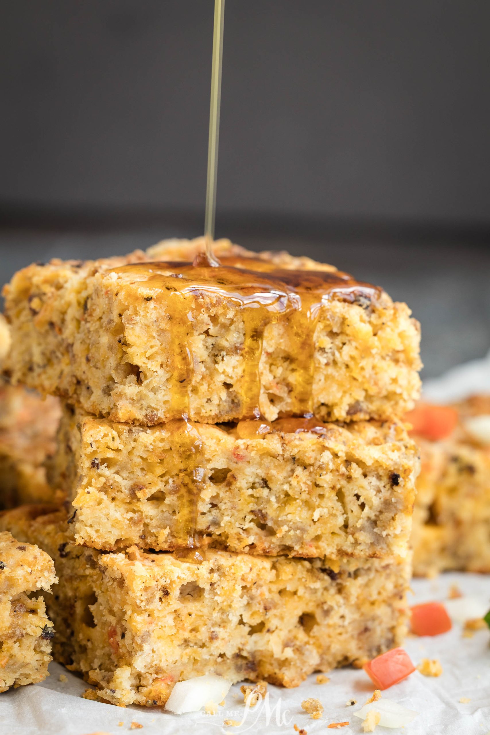 Three pieces of oat and carrot cake stacked on top of each other, with syrup being poured over the top piece.