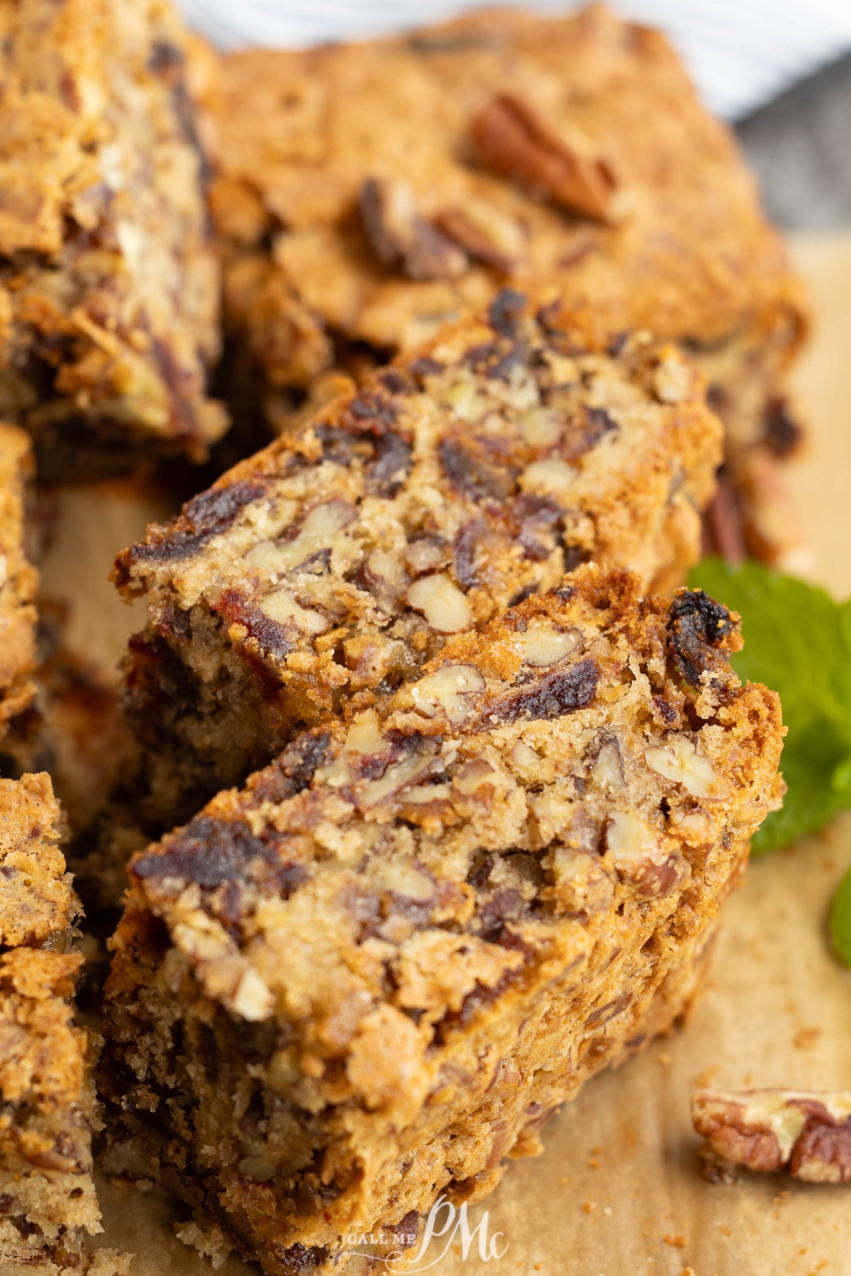 Close-up of sliced pecan date loaf bars on parchment paper, showing a dense texture with visible chunks of pecan and date.