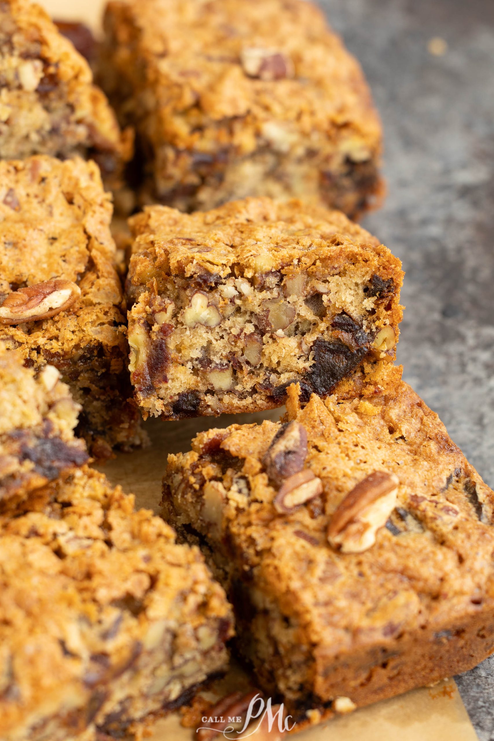 Close-up of several Old Fashioned Date Nut Bread with visible nuts and a golden-brown crumb, arranged on a sheet of parchment paper.