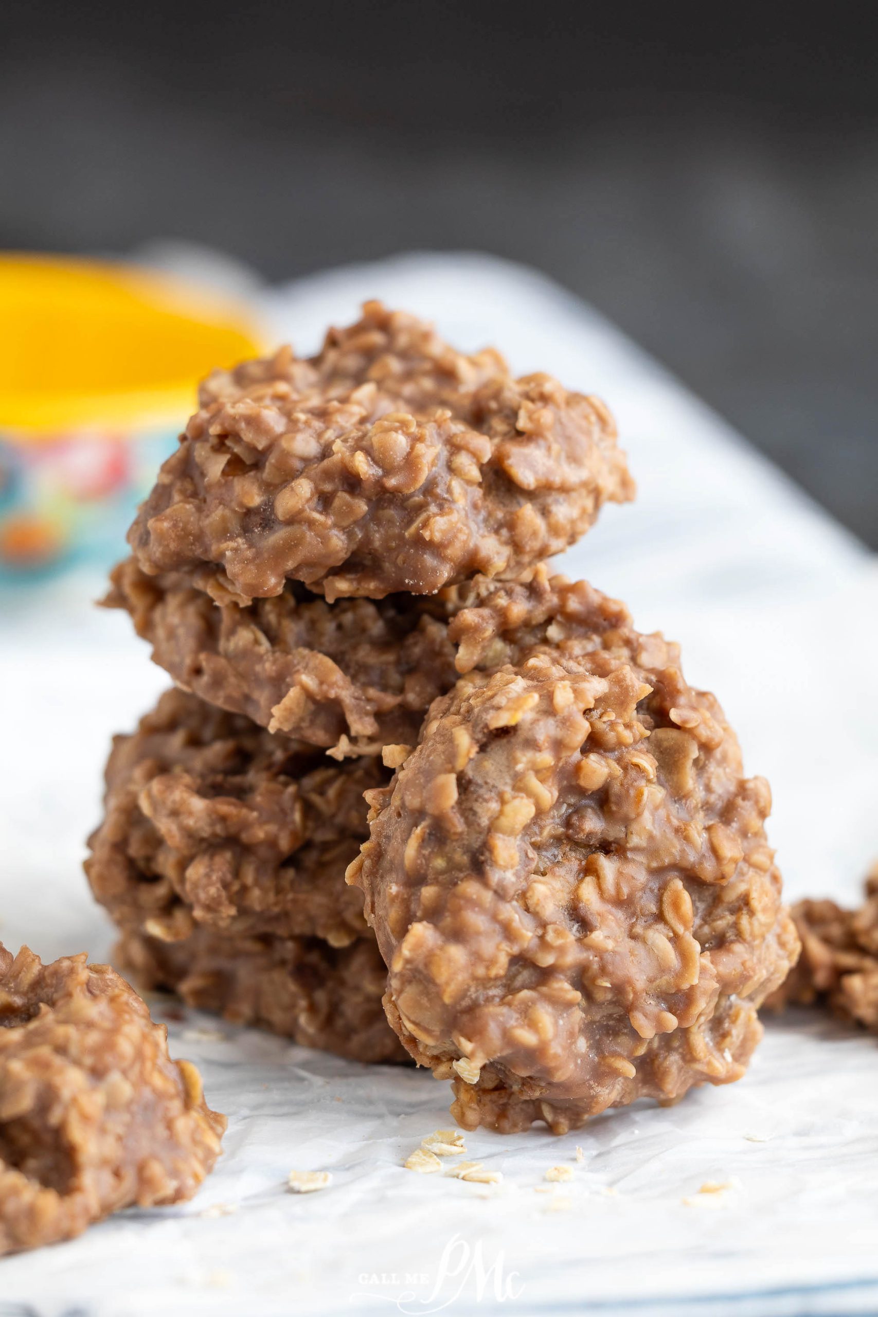 Three biscuits are stacked on a white surface, with a blurred yellow and floral bowl in the background.