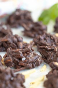 Clusters of chocolate-covered pretzel sticks and nuts are arranged on a white surface.
