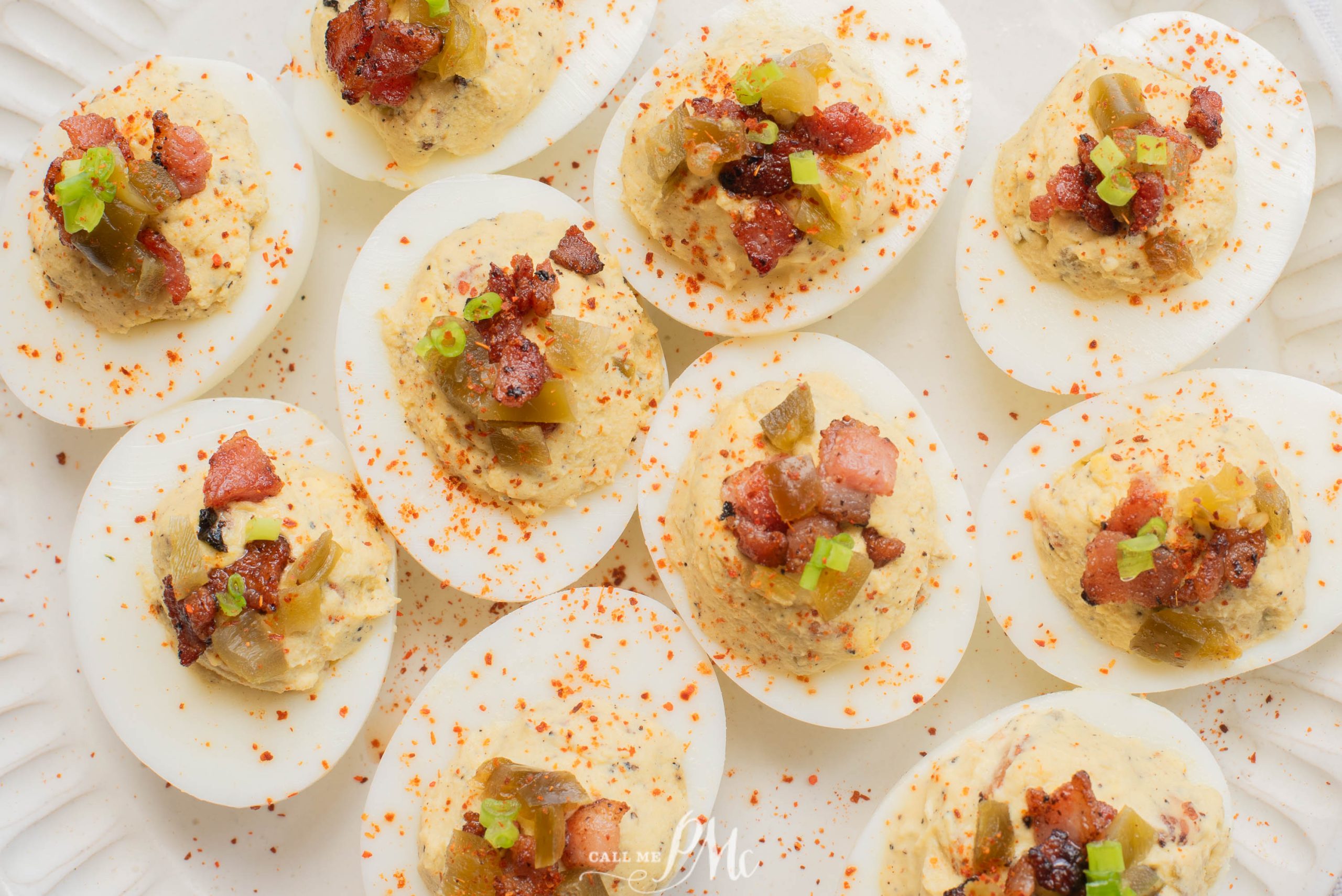 Appetizer with bacon pieces, diced green onions, pickles, and a sprinkle of paprika, arranged on a white plate.