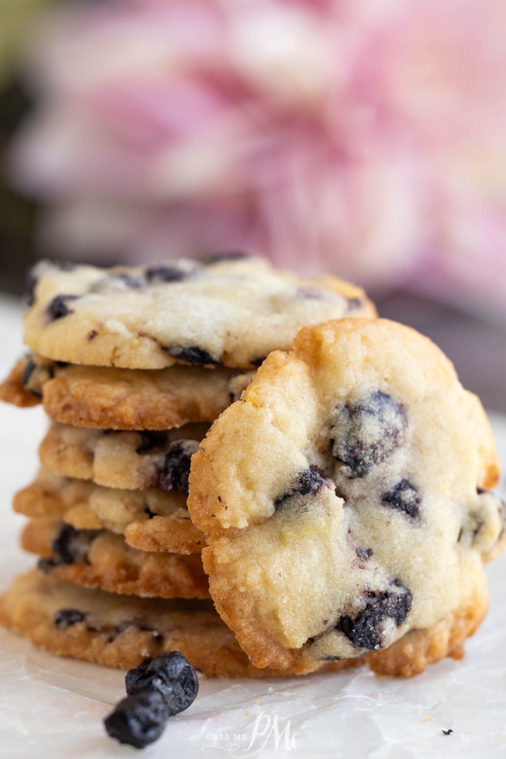 A stack of Dried Blueberry Lemon Cookies on a marble surface with a blurred pink flower in the background.