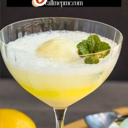 A refreshing limoncello float in a glass garnished with mint, with lemons and a spoon on a wooden surface. Text at the top reads, "Limoncello Float callmepmc.com.