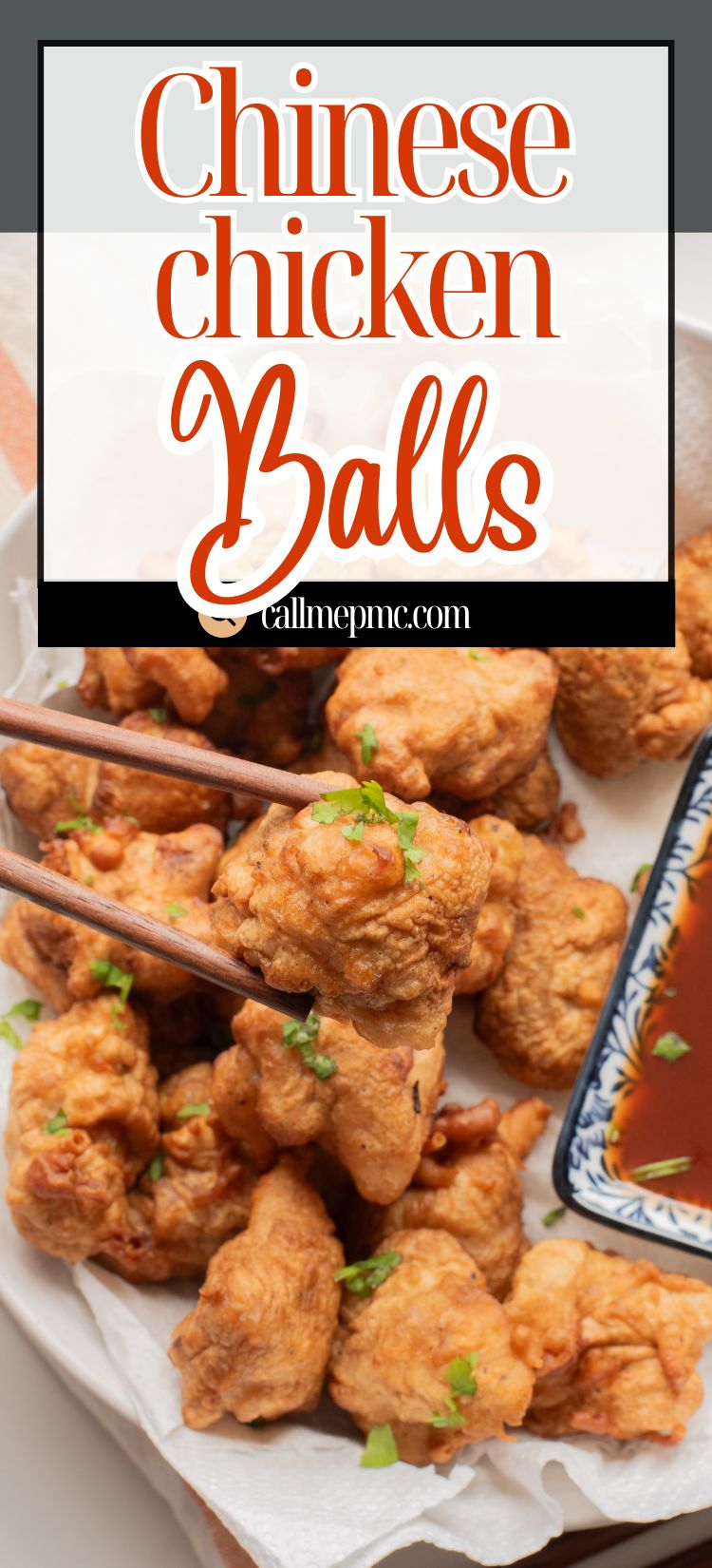 A plate of fried Chinese chicken balls garnished with herbs, with chopsticks holding one piece and a dish of dipping sauce on the side.
