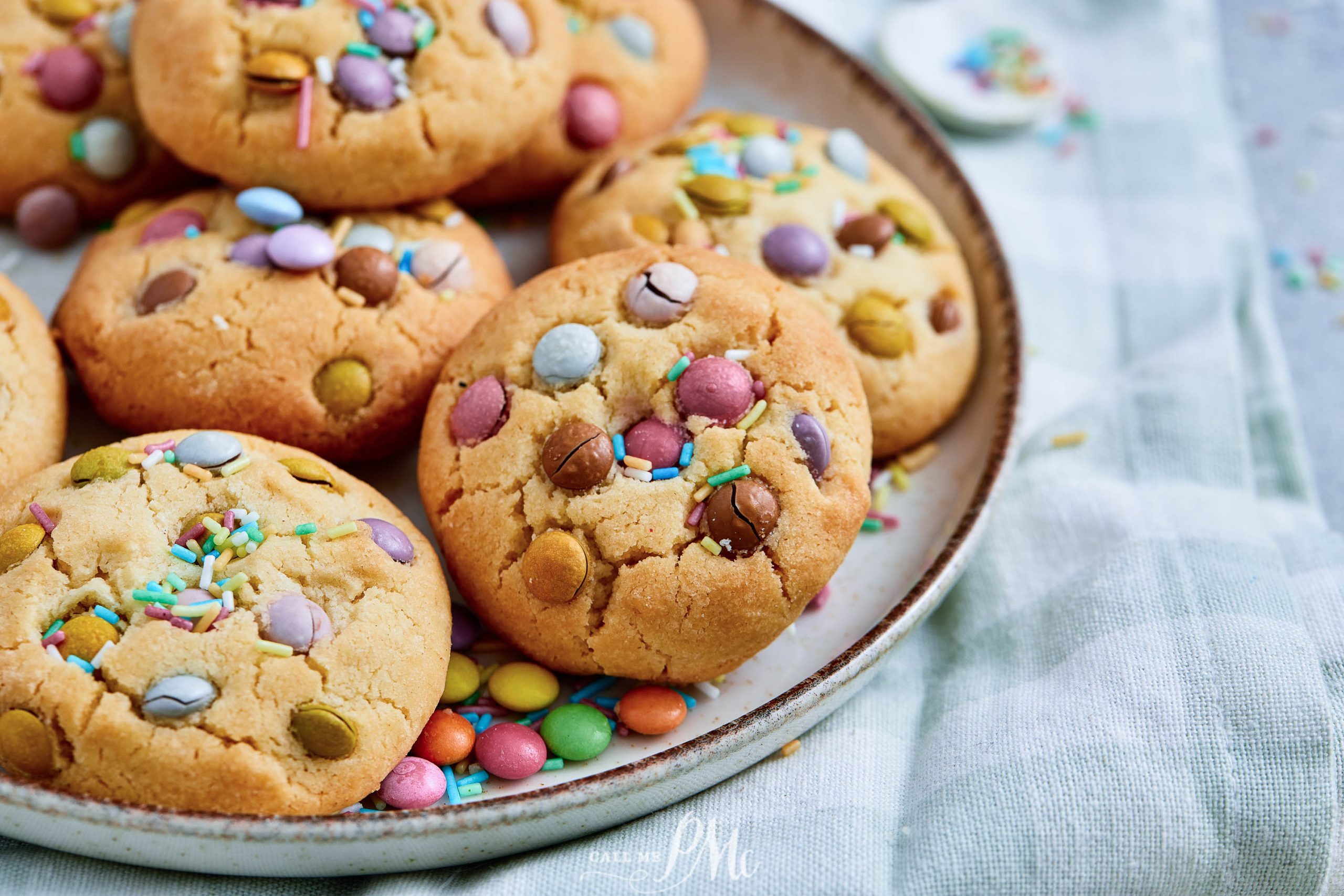 A plate of desserts topped with colorful chocolate candies and sprinkles, with extra candies scattered on the plate.