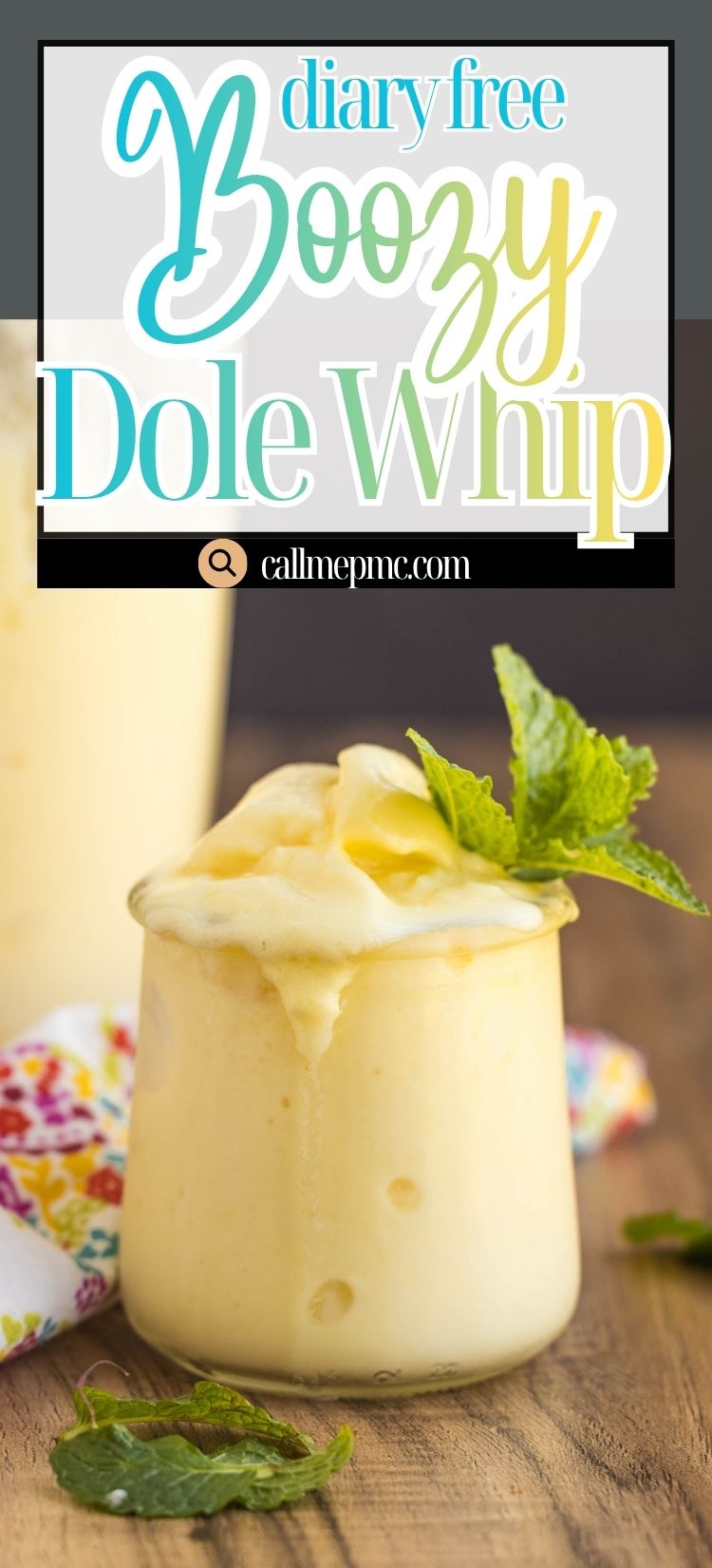 A glass jar filled with creamy yellow boozy Dole Whip, garnished with a mint sprig, sits on a wooden table next to a floral napkin.